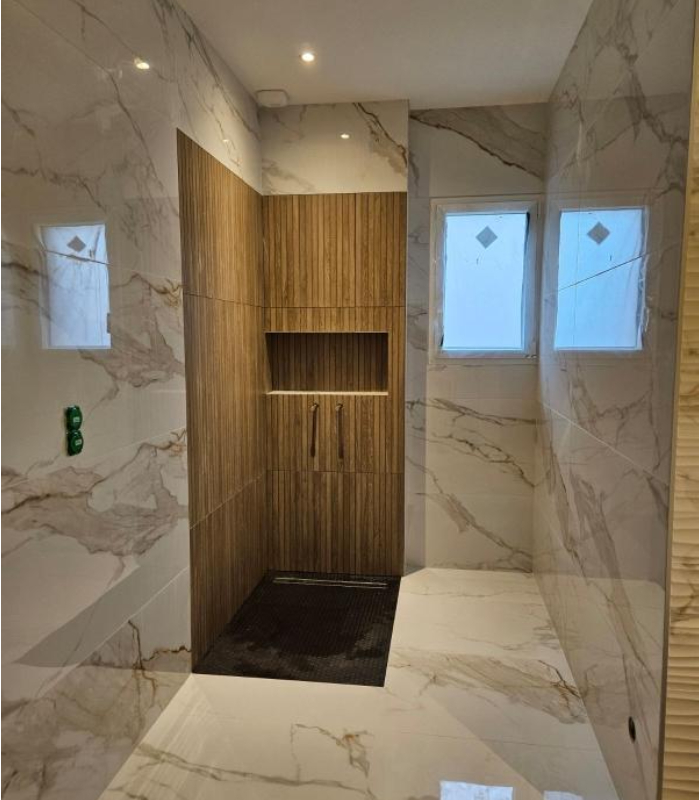 Douche à l’italienne carrelage grand format effet marbre et niche murale bois