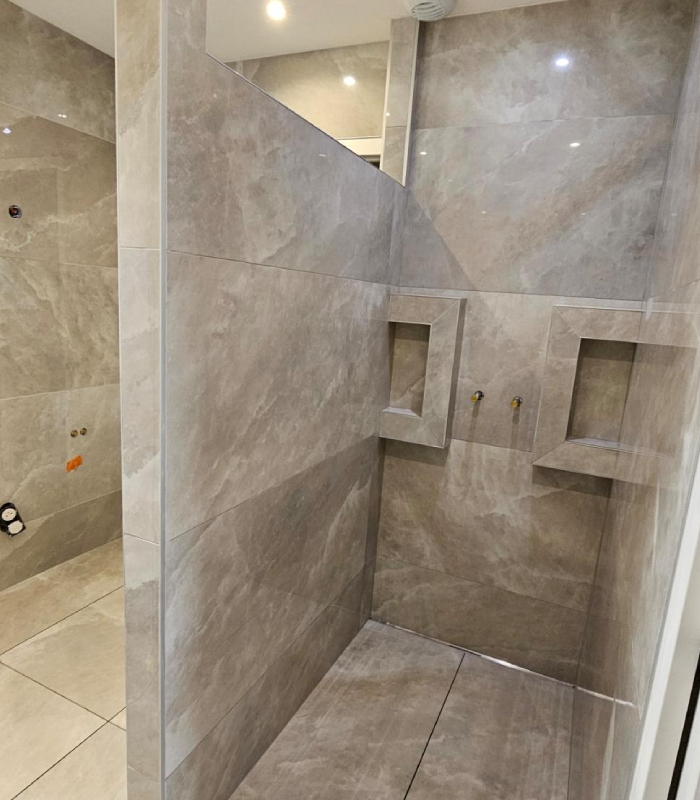 Douche carrelée effet pierre avec niches murales intégrées et pose grand format